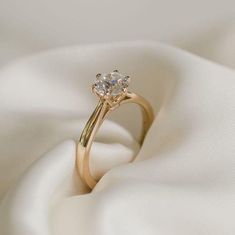 a gold ring with two diamonds on it sitting on a white satin fabric, close up