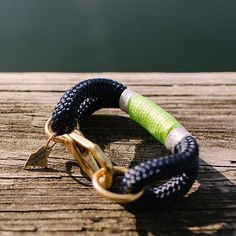 a close up of a bracelet on a wooden surface with water in the back ground