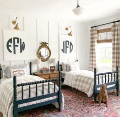 two twin beds in a bedroom with plaid bedding and curtains on the windowsill