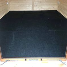 the inside of a wooden enclosed area with black flooring