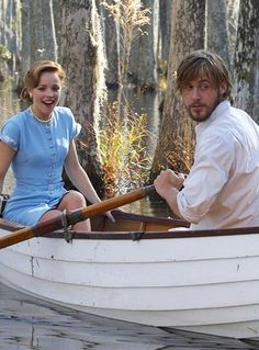 a man and woman in a boat on the water with trees behind them, both smiling