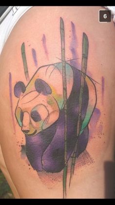 a panda bear tattoo on the back of a woman's thigh with bamboo stalks