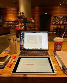 an open laptop computer sitting on top of a wooden table next to a cup of coffee