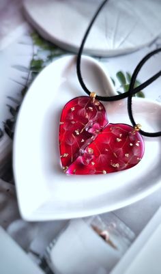 a red heart shaped glass pendant on a black cord