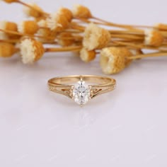 a diamond ring sitting next to dried flowers