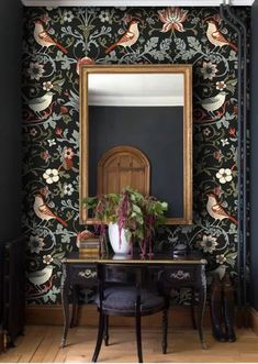 an ornate wallpapered room with a mirror and desk in front of the mirror