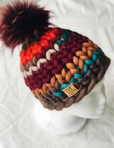 a knitted hat with a fur pom sits on a mannequin head