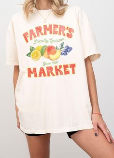 This Farmer's Market T-Shirt offers a relaxed adult fit and is made with heavyweight Comfort Colors for ultimate comfort. The trendy vintage retro design features a typography of "Farmer's Market - Locally Grown" with a colorful illustration of peach, lemon, and berry. Show your support for local produce while looking stylish and feeling comfortable. S:M:L:XL *Size Chart Available Garment Dyed Cotton 100% Machine Wash Delicate cycle with like colors Vintage Short Sleeve T-shirt With Lettering, Vintage Text Print T-shirt For Spring, Retro Faded T-shirt With Letter Print, Faded T-shirt With Text Print In Relaxed Fit, Faded T-shirt With Text Print And Relaxed Fit, Relaxed Fit Faded T-shirt With Text Print, Faded Retro T-shirt For Summer, Oversized Vintage T-shirt For Spring, Vintage Oversized Soft-washed T-shirt