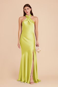 a woman wearing a lime green dress with high slits and an asymmetrical neckline