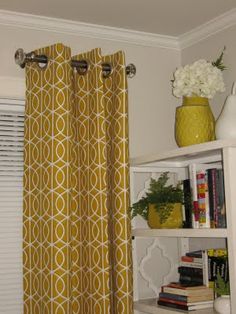 the curtains in this room are yellow and white, while the bookshelf is next to the window