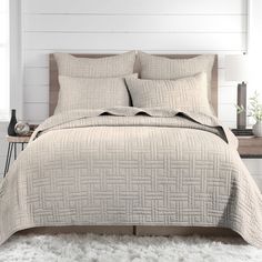 a bed with white sheets and pillows on top of it in front of a wooden headboard