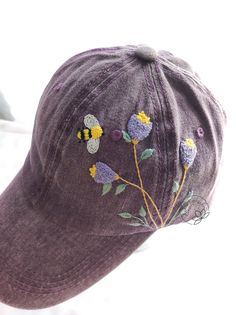 a purple hat with bees and flowers on it's brimmed visor