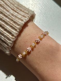 Meet the "Rosemarie" bracelet, a delicate flower beaded bracelet made with baby pink, golden, and cream pearlescent seed beads. Its dainty, feminine design and neutral palette make it a versatile accessory that effortlessly complements any outfit. Whether you're dressing up for a special occasion or adding a subtle elegance to your everyday attire, the "Rosemarie" bead bracelet is your perfect companion. Embrace its timeless charm and understated beauty - explore the 'Rosemarie' flower beaded br Delicate White Bracelets For Spring, White Delicate Bracelet For Spring, Delicate White Bracelet For Spring, White Feminine Round Bead Bracelets, Feminine White Round Bead Bracelets, White Round Beads Feminine Bracelet, White Feminine Bracelets With Round Beads, Feminine White Round Beaded Bracelets, Adjustable Pink Pearl Bracelet Feminine Style