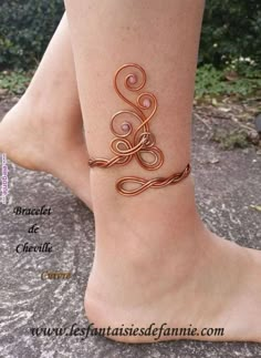 a woman's foot with a copper wire bracelet on her left ankle and the word love written in it