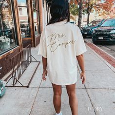 a woman is walking down the sidewalk wearing a t - shirt that says miss cooper