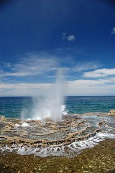 an old - fashioned geyser spewing out water into the ocean on a sunny day