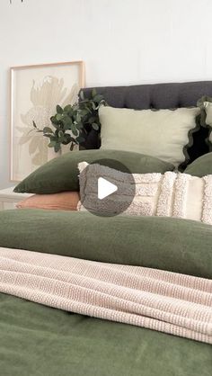 a bed with green sheets and pillows in a bedroom next to a potted plant