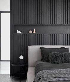 a black and white bedroom with a bed, night stand and lamp on the wall