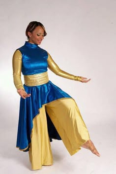 a woman in a blue and gold outfit is dancing with her hands out to the side