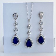 I've created this absolutely gorgeous long luxury blue sapphire cubic zirconia bridal set in rhodium plated brass setting. This set includes: #Earrings feature a large teardrop with pear cut blue sapphire cubic zirconia center surrounded by tiny round zirconia crystals. Teardrop dangles from a bright cubic zirconia ear stud and two round cubic zirconia connectors. Total length of the earring is 6 cms. #Necklace pendant features a large teardrop with pear cut blue sapphire cubic zirconia center s Sapphire Jewelry With Sparkling Stones For Wedding, Sapphire Dangle Jewelry For Wedding, Elegant Pear-shaped Blue Jewelry, Elegant Blue Pear-shaped Jewelry, Sapphire Cubic Zirconia Wedding Jewelry, Sapphire Cubic Zirconia Jewelry For Wedding, Teardrop Sapphire-colored Cubic Zirconia Jewelry, Teardrop Sapphire Cubic Zirconia Jewelry, Elegant Sapphire Bridal Necklace In Cubic Zirconia