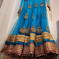 This Is An Amazing Blue Anarkali Dress With Matching Pants And Scarf. The Fabric Has Shining Gold Accents. This Will Make A Great Choice For Any Occasion. Blue Cutdana Anarkali Set For Festivals, Blue Cutdana Anarkali For Festivals, Blue Anarkali Set With Sheer Dupatta For Navratri, Blue Anarkali Sharara For Festivals, Traditional Blue Anarkali Set Maxi Length, Blue Dabka Anarkali Set For Diwali, Blue Bollywood Anarkali Set For Designer Wear, Traditional Blue Maxi Anarkali Set, Blue Maxi Length Sharara With Cutdana