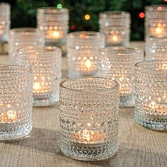 there are many glasses that have candles in them on the table next to each other