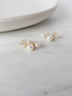 The Suave Cluster Earrings are a stunning accessory that will elevate any outfit with their timeless design. The floral clusters of glass crystals and pearls create an elegant and glamorous look that's perfect for special occasions. Crafted with a chic gold finish and friction back, these earrings are not only beautiful but also high-quality and durable. They sit gracefully on the earlobe, making them a perfect addition to any look. Whether you're planning a romantic date night or attending a wedding as a guest, the Suave Cluster Earrings will add a touch of sparkle and shine to your outfit. They're versatile enough to complement any dress, adding a touch of sophistication and glamour to your style. If you're a bride-to-be or a member of a bridal party, these earrings are also an excellent Elegant Gold Ear Climbers For Wedding, Dainty Crystal Earrings For Formal Events, Dainty Crystal Earrings For Formal Occasions, Elegant Wedding Cluster Earrings With Ear Wire, Dainty Ear Wire Bridal Earrings For Anniversary, Gold Elegant Crystal Earrings For Bridesmaid, Dainty Bridal Earrings With Ear Wire For Anniversary, Elegant Wedding Ear Climbers, Elegant Crystal Ear Wire Earrings For Wedding