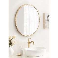 a white sink sitting under a round mirror next to a wall mounted faucet