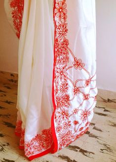 "Stunning half white semi silk saree with intricate all over embroidery and semi raw silk unstiched blouse in reddish orange. The red color thread embroidery is simply stunning aginst offwhite. The entire embroidery is hand worked and the floral border extends more in the front, pallu and the pleats. Saree length 5.5 meters Blouse fabric 1 meter 44\" wide Saree ships in 2-3 days of payment. Delivery within 4-5 days of shipment all over the world. We also offer blouse and petticoat stitching for White Silk Traditional Wear With Floral Embroidery, Off White Traditional Wear With Floral Embroidery In Mulmul, Red Traditional Wear With Floral Embroidery, Off White Mulmul Dupatta With Embroidered Border, White Silk Traditional Wear With Embroidered Border, Off White Chanderi Traditional Wear With Floral Embroidery, Red Chikankari Embroidered Fabric For Wedding, White Traditional Wear With Floral Embroidery, Red Traditional Wear With Floral Embroidery For Ceremonies