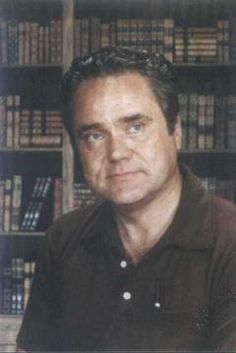 a man sitting in front of a bookshelf with many books on the shelves