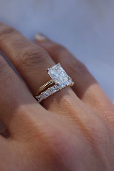 a woman's hand with a diamond ring on top of her finger and the other hand holding an engagement ring