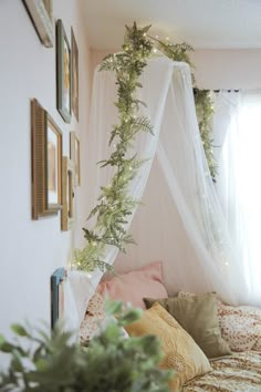 a canopy bed with white netting and green garland hanging from it's sides in a bedroom