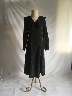 "vintage 1990s handmade dress shiny black jacquard fabric w/floral pattern  zip back ruffle collar long sleeve empire waist ruffle neck unlined good vintage condition, light wear no size tag-see below measures, lying flat, shoulder-17\" chest-17\" waist-15\" hip-21\" sleeve-22 1/2\" length-48\" (4')" Vintage V-neck Winter Dress, Fitted Long Sleeve Black Vintage Dress, Black Vintage Dress With Ruffles For Fall, Fitted Vintage Winter Dress, Black Long Sleeve Vintage Dress For Fall, Long Sleeve Vintage Evening Dress For Fall, Long Sleeve Vintage Dress With Ruffles For Fall, Fall Vintage Long Sleeve Dress With Ruffles, Black Long Sleeve Vintage Dress