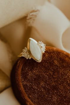 a white ring sitting on top of a wooden table next to a white cloth covered pillow