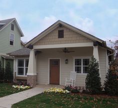 a house that is in the middle of some grass and flowers on the front lawn