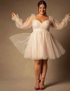 a woman in a short white dress posing for the camera with her arms spread out