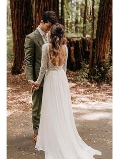 a bride and groom standing in the middle of a forest holding each other's hands