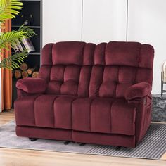 a red reclining sofa in a living room with a rug and potted plant