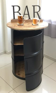 a barrel shaped table with two mugs on it and the word bar written in large letters