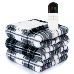 three black and white towels stacked on top of each other with thermometer in front of them