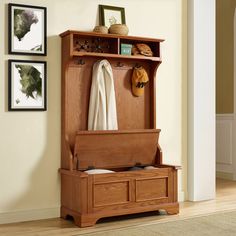 a wooden bench sitting next to a wall with pictures on the wall and a coat rack