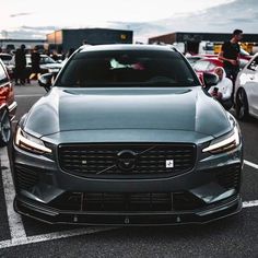 the front end of a car parked in a parking lot with other cars behind it