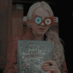 a woman holding up a magazine with googly eyeballs on her face and looking at the camera