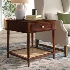 a small table with a lamp on it in front of a white chair and couch