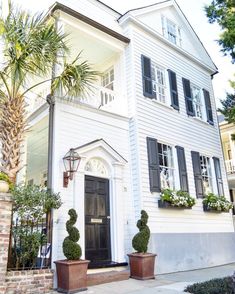 a white house with black shutters and potted plants