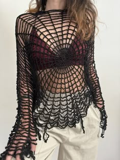 a woman with long hair wearing a black and red crochet top