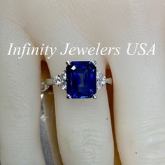 "This ring is an emerald cut lab created blue sapphire with round moissanite sides, 14k white gold # 6312 We feature the finest quality of lab grown sapphires in the world. The properties of lab-grown are physically, chemically and visually identical to natural, just grown in a lab setting. -Approximate total carat weight: 3.85ctw. diamond equivalent -Center Stone Size: approx. 3.55ct. diamond equivalent -Center Stone Shape: emerald cut 10x8mm -Gem Type: lab created blue sapphire -Stone Clarity: Blue Radiant Cut Lab-created Sapphire Jewelry, Blue Sapphire Emerald Cut Promise Ring, Fine Jewelry Emerald Cut Diamond Ring With Lab-created Sapphire, Blue Sapphire Radiant Cut Promise Ring, Emerald Ring With Sapphire Accent Stones, Blue Radiant Cut Sapphire Promise Ring, Emerald Cut Sapphire Jewelry For Proposal, Blue Radiant Cut Sapphire Ring In Sterling Silver, Blue Solitaire Sapphire Ring Emerald Cut