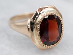 a gold ring with a large red stone in the center on a white tablecloth