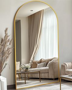 a living room filled with furniture and a large gold framed mirror on the wall next to a couch