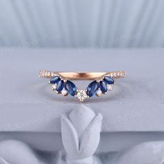 a gold ring with blue and white stones on it, sitting on top of a table